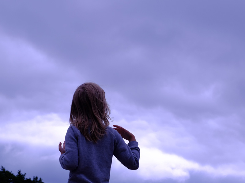 Child looking up at clouds in sky